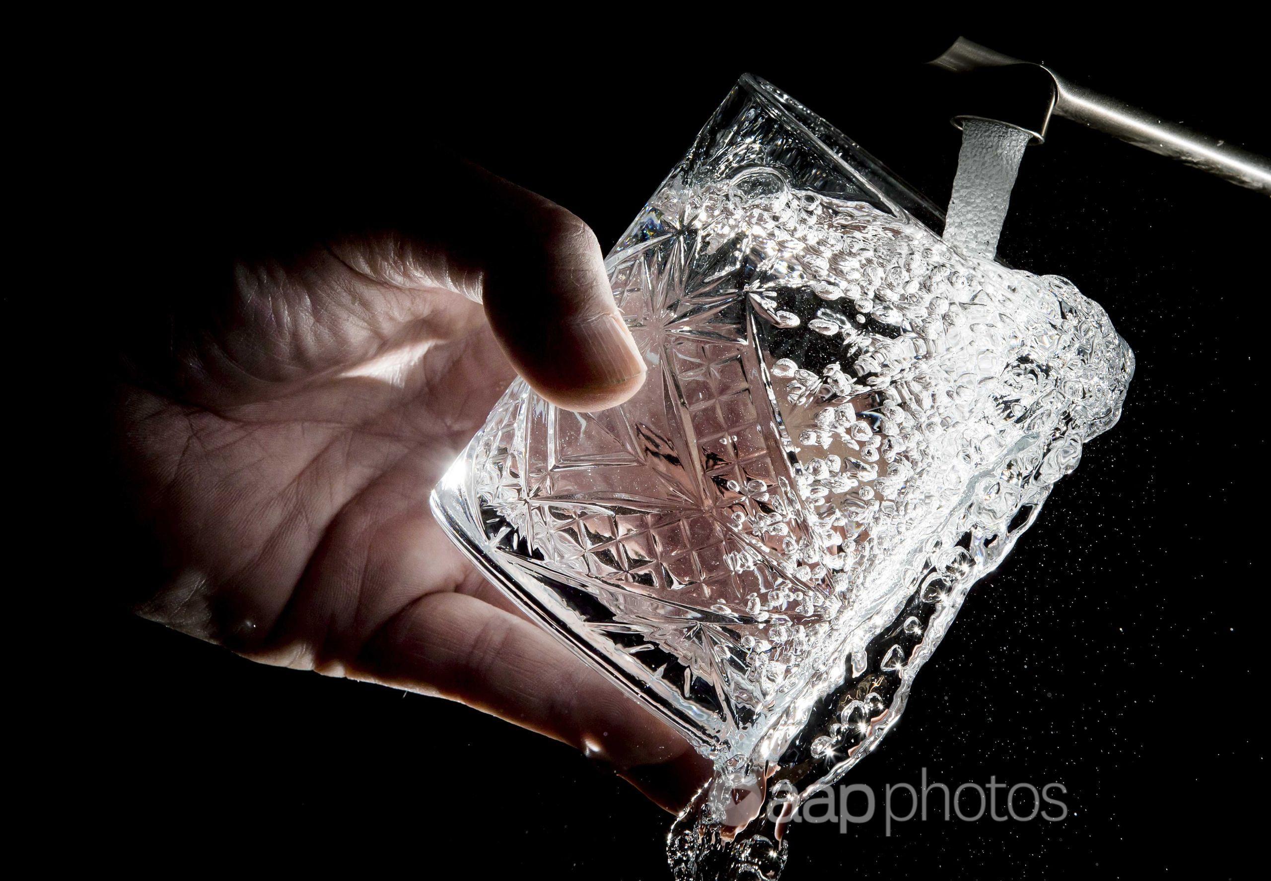 Water from a tap is poured into a glass.