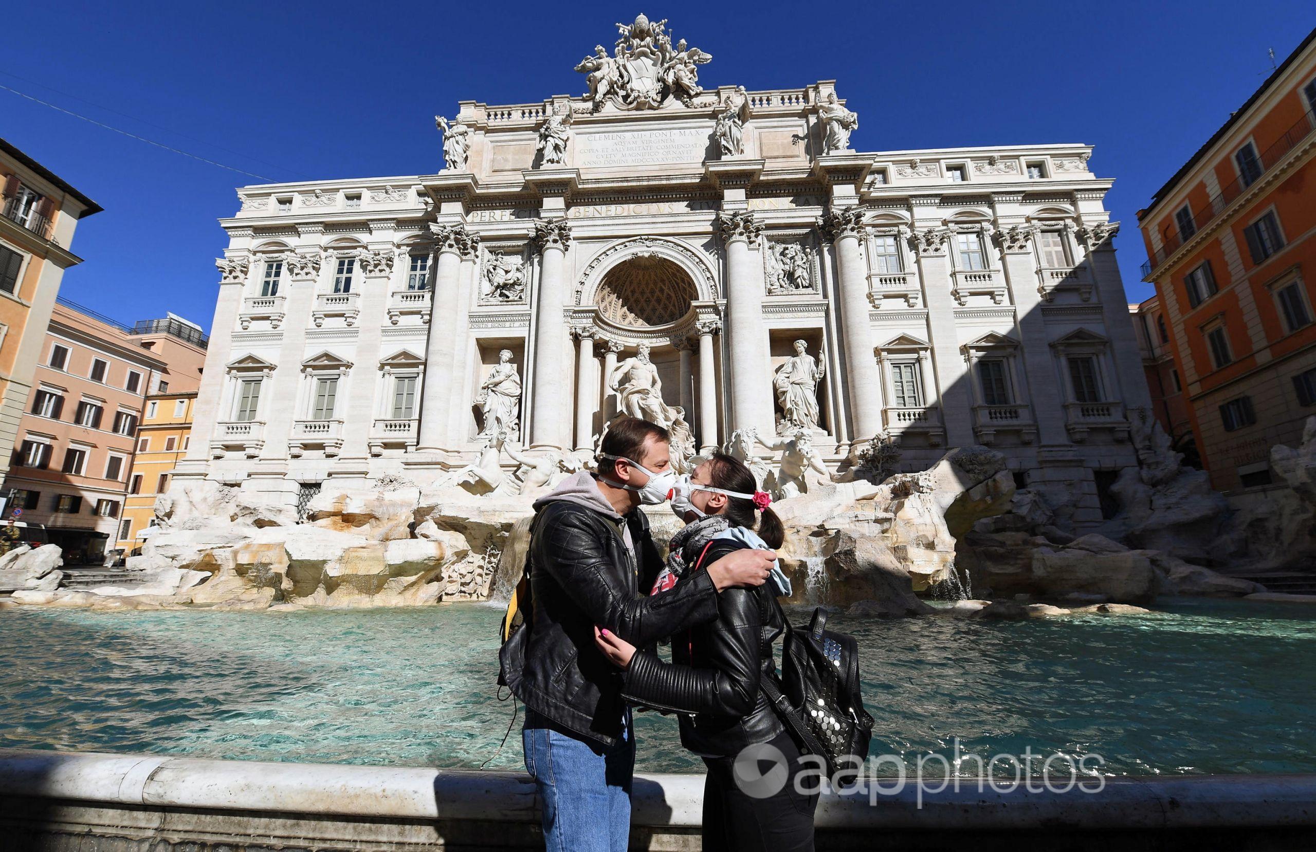 Tourists kiss in front of the Fontana di Trevi in Rome.