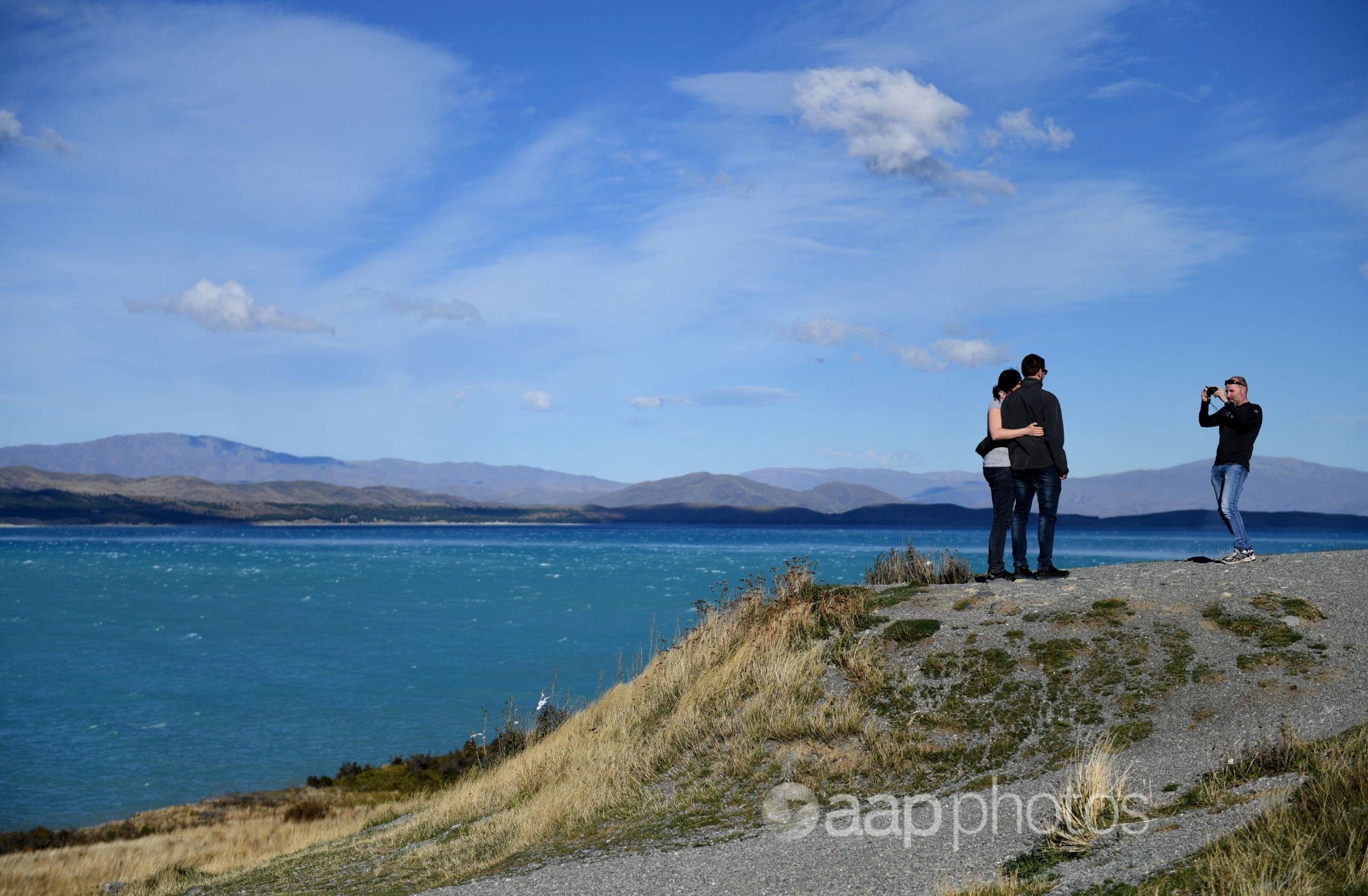 Couple has their photo taken on the shore of a lake in NZ
