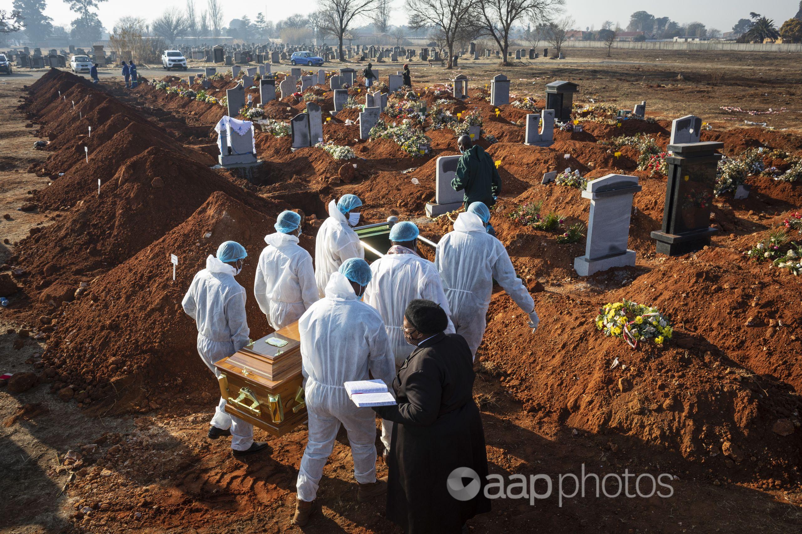 Gravediggers in protective suits carry the coffin of a COVID-19 victim