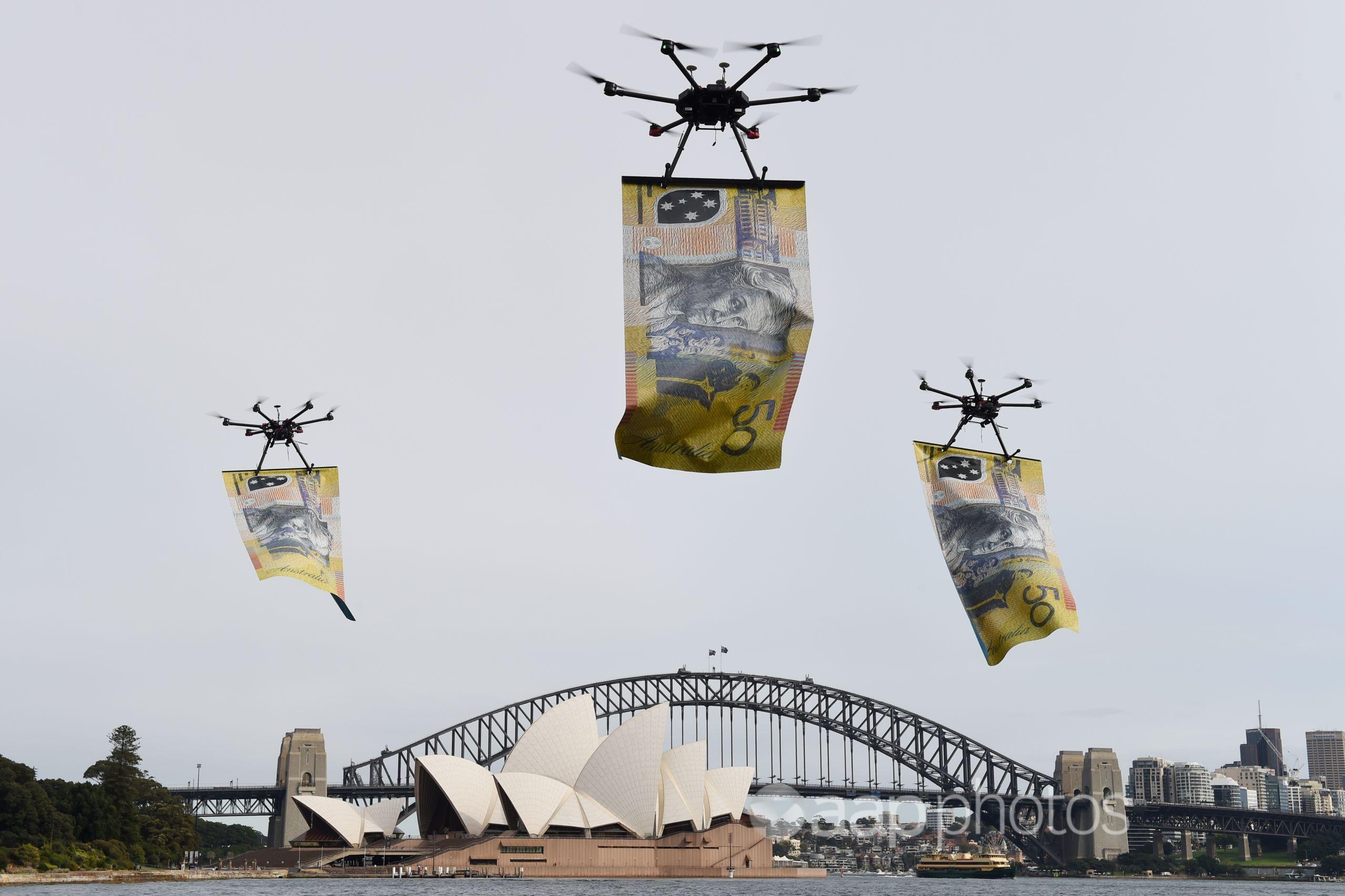 Drones carrying giant  notes are flown over Sydney Harbour.