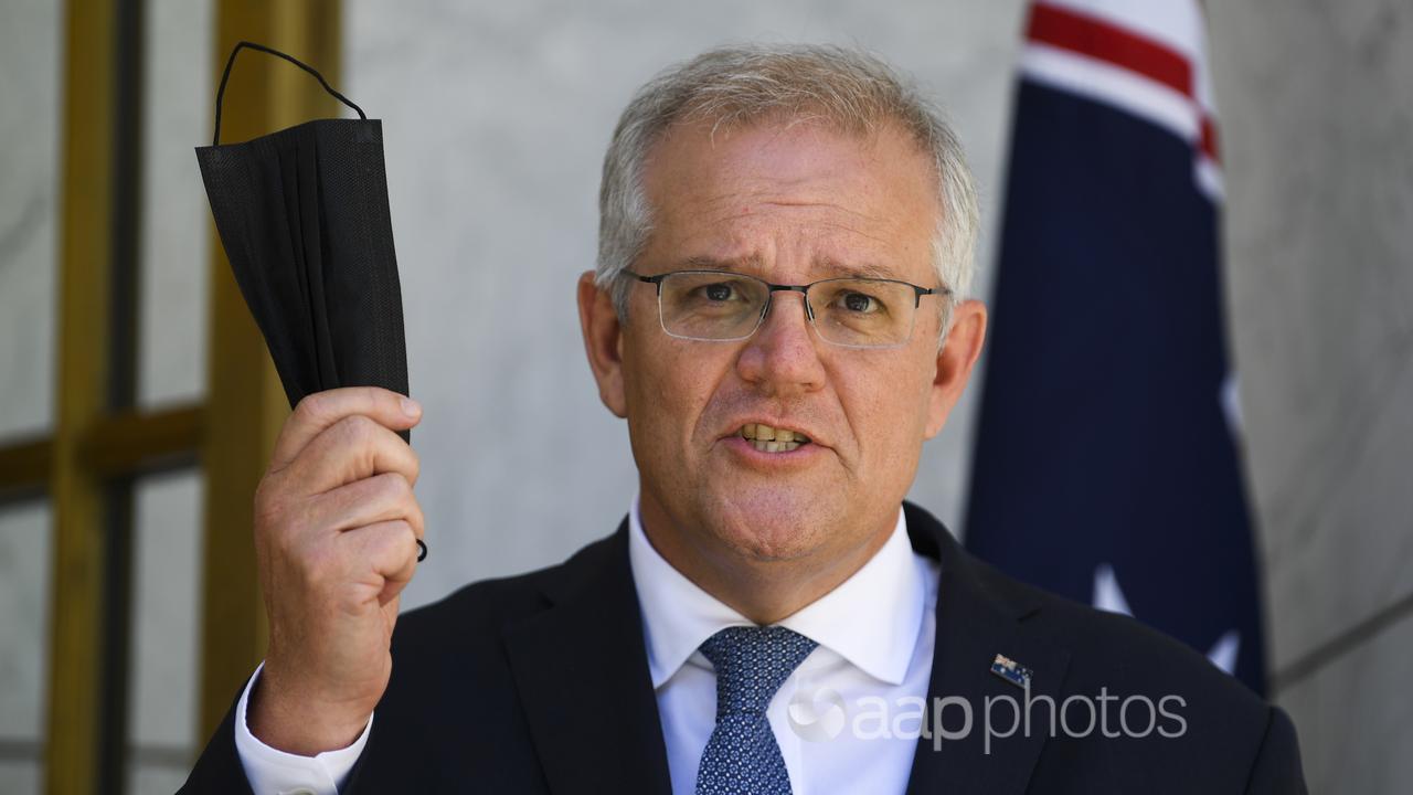 Scott Morrison pictured holding up a mask (AAP Image/Lukas Coch)