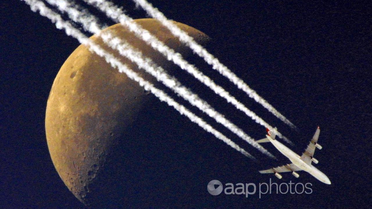 Contrails seen coming from a plane flying past the moon