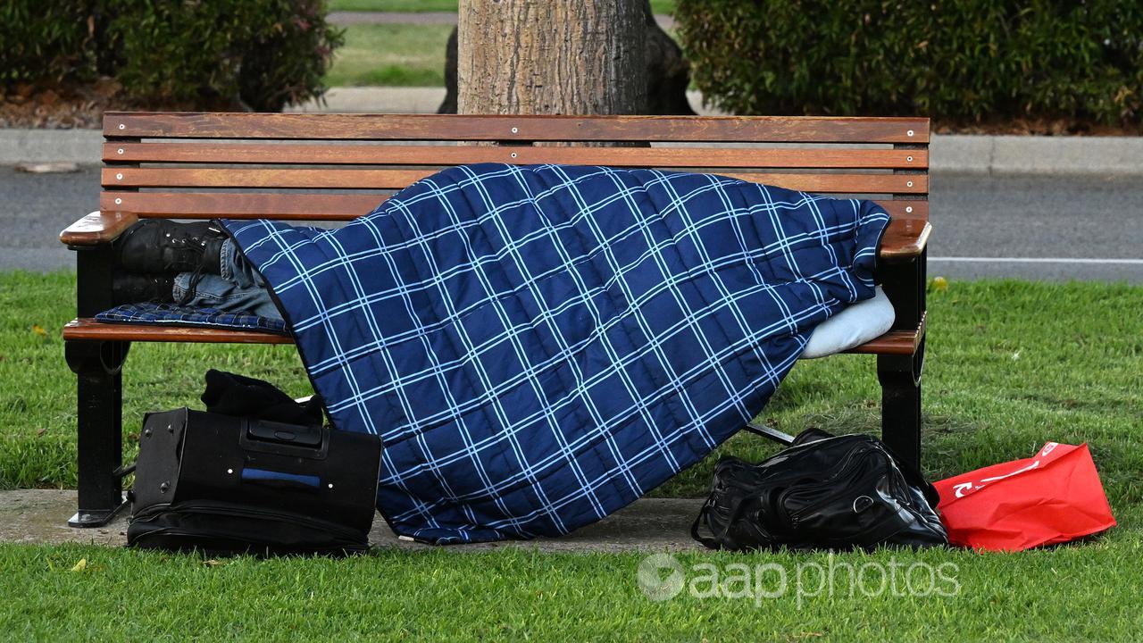 A homeless person is seen sleeping on a park bench in Perth