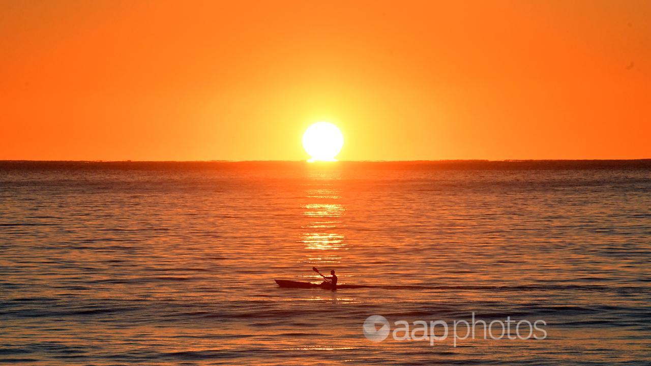 A kayaker paddles at sunrise at Manly Beach in Sydney.