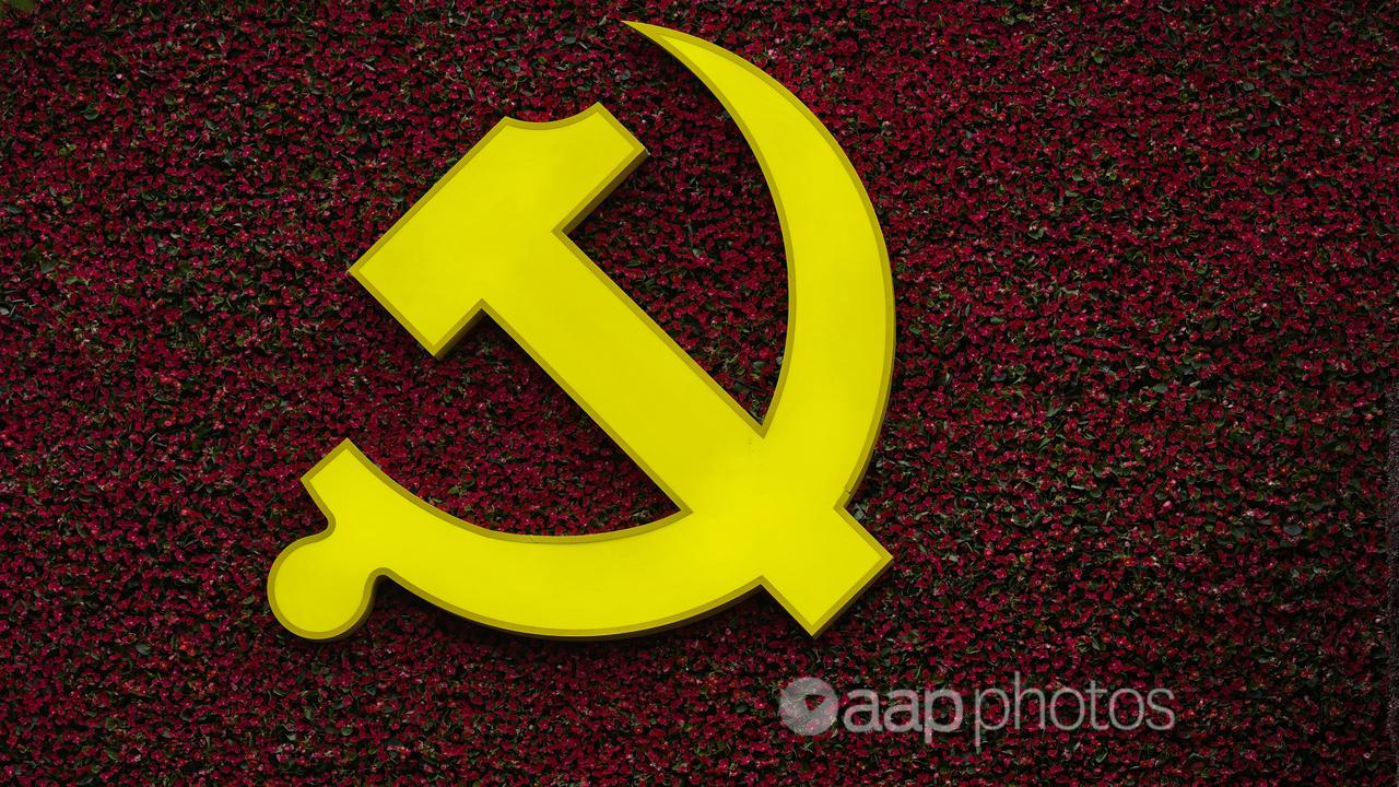 A worker puts flowers on a decoration with Communist logo in Beijing.