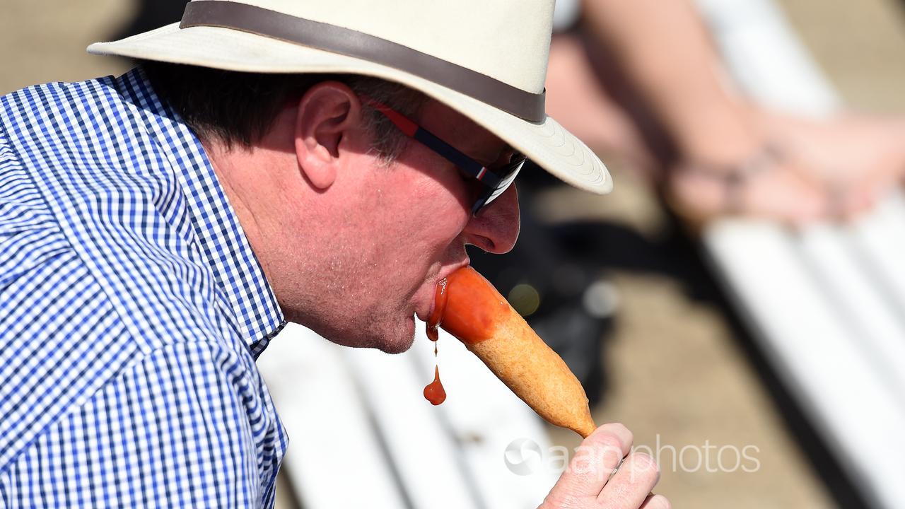 A man eating a Dagwood Dog at a show