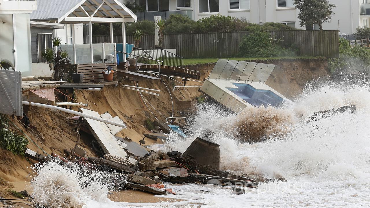 Waves crash against a beachfront property in Sydney.