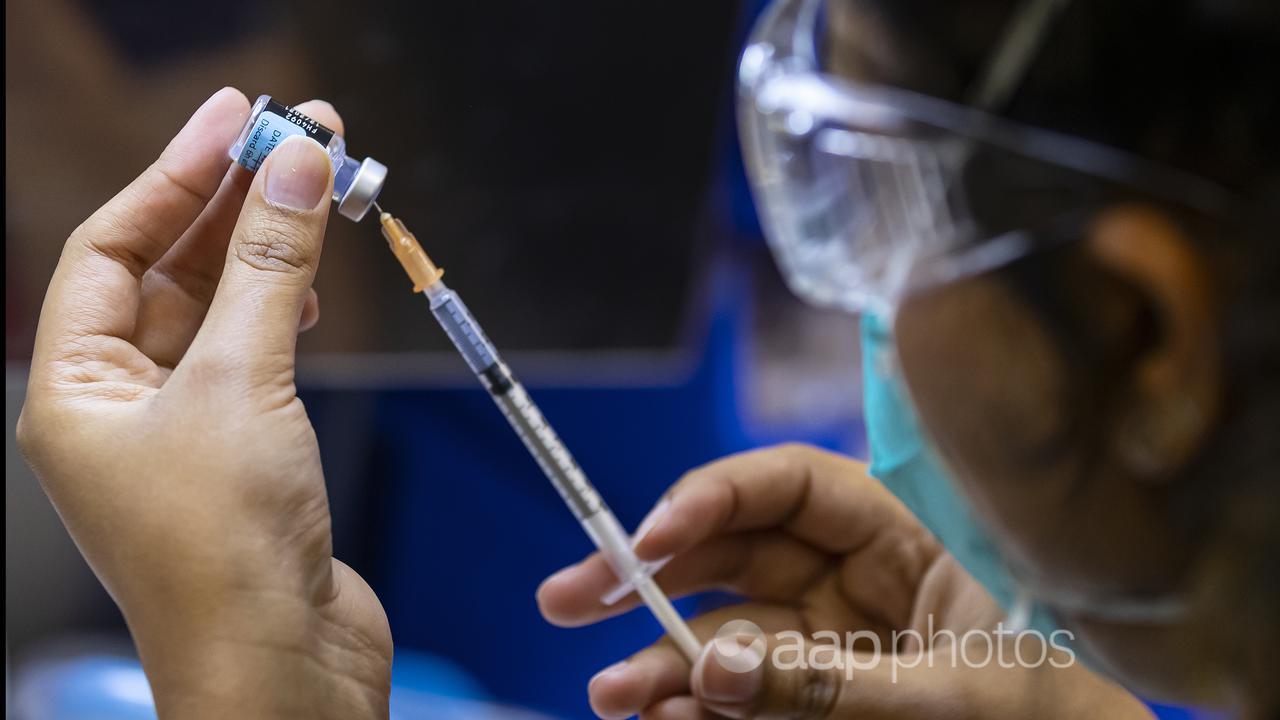 A healthcare worker prepares a Pfizer vaccine (file image)