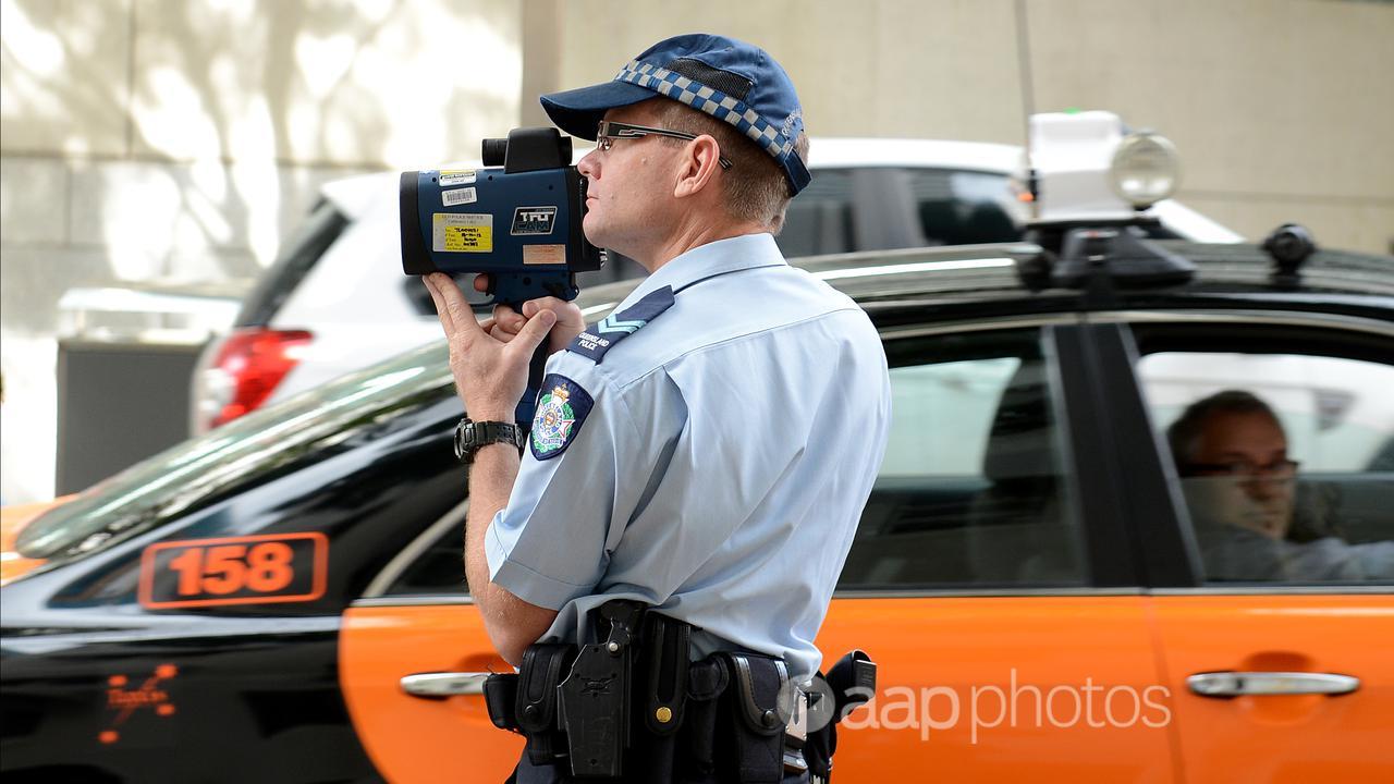 A Queensland police officer operates a speed radar (file image)