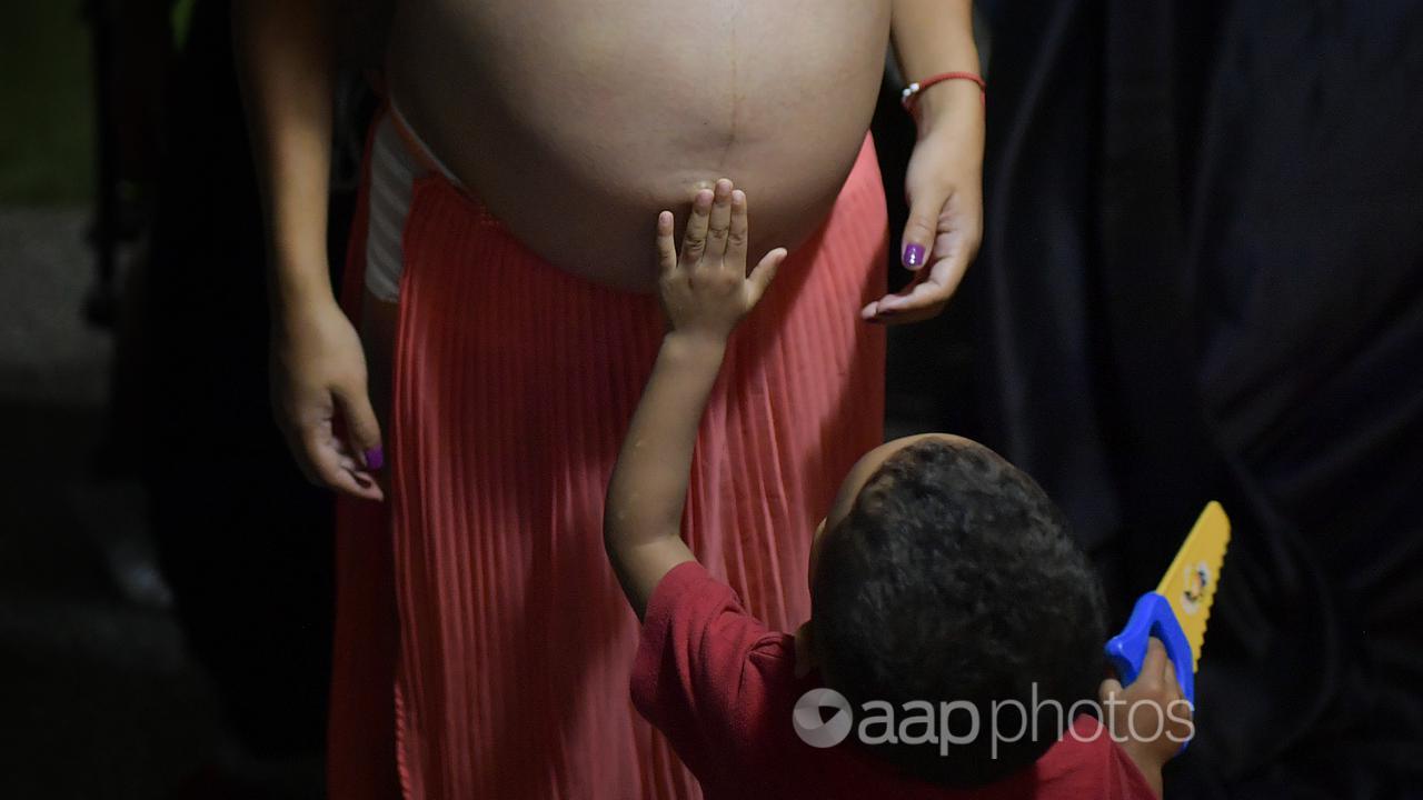A small boy touches a pregnant woman's navel (file image)
