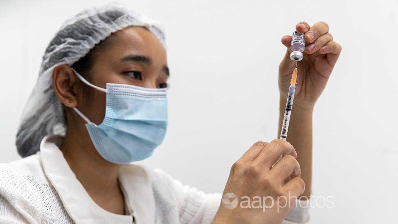A health care worker fills a syringe at a COVID-19 clinic