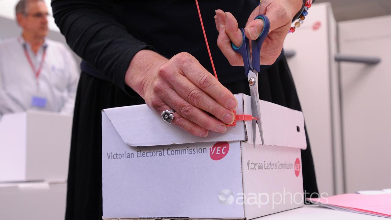 The seal of a ballot box is cut by a VEC staffer