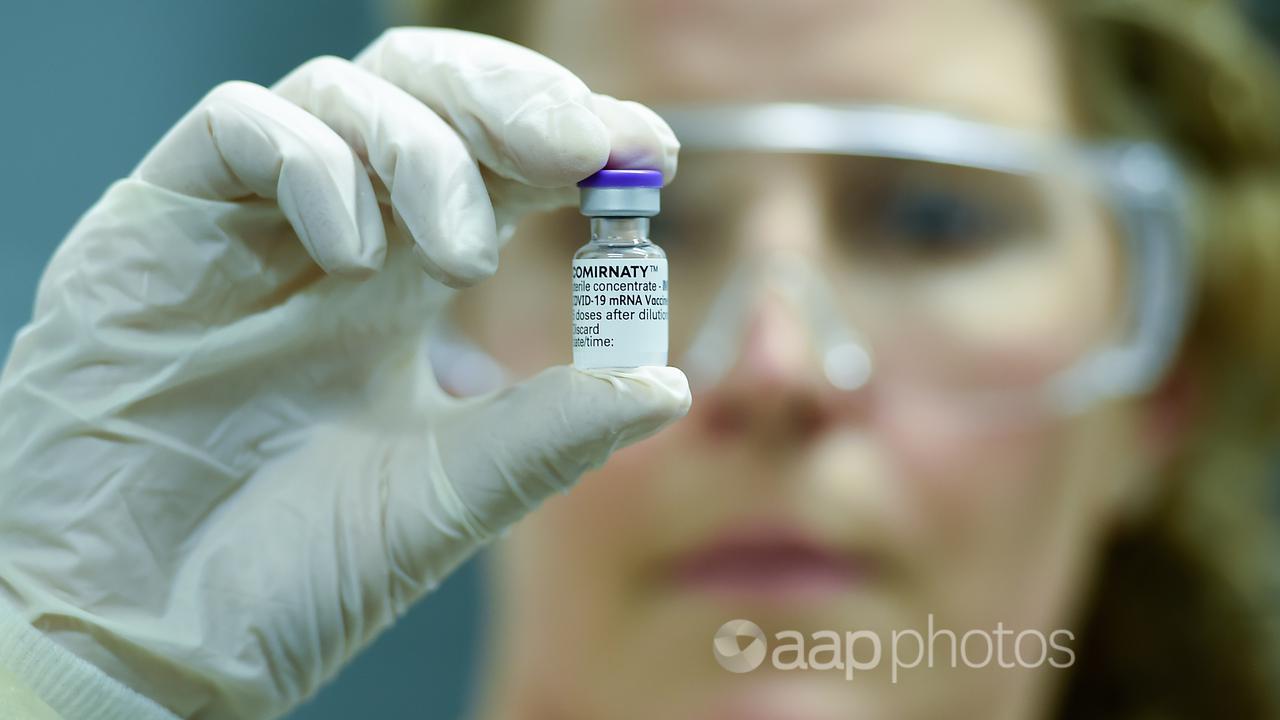 A Queensland hospital staffer holds a vial of the Pfizer COVID vaccine