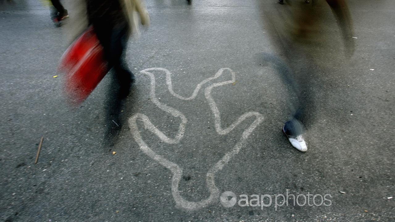 People pass by a painted outline of a dead body in Athens