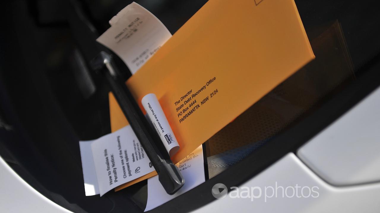 A parking ticket sits underneath a windscreen wiper on a vehicle