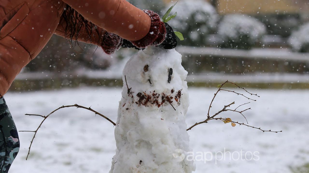 People build a snowman as snow falls (file image)