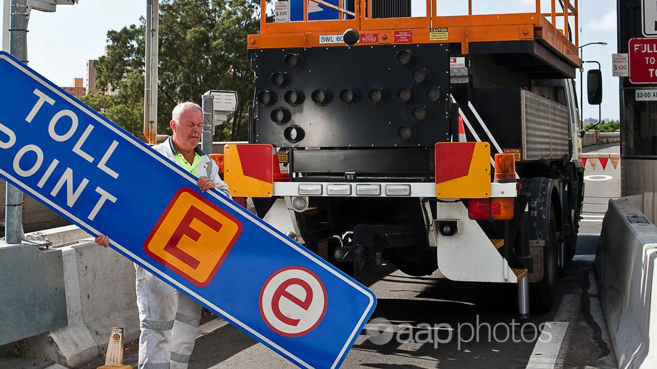 A worker dismantling cash toll booth sign on the Sydney Harbour Bridge