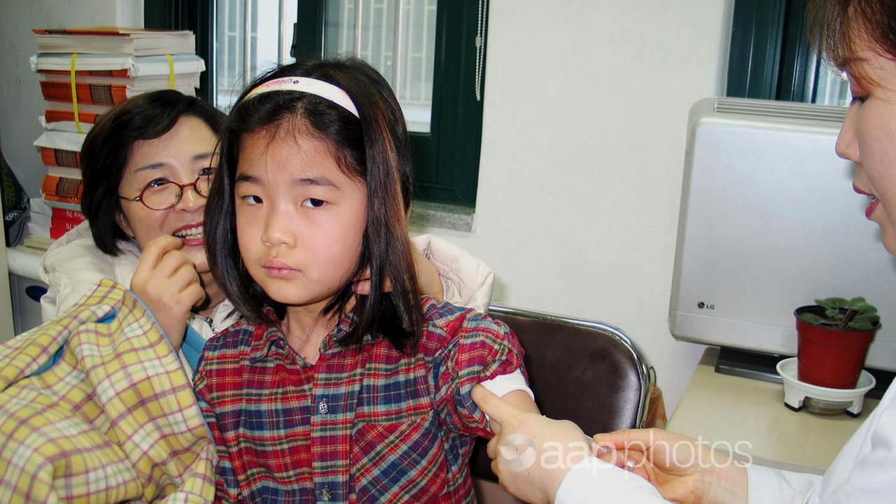 A young girl receives a vaccination against measles.