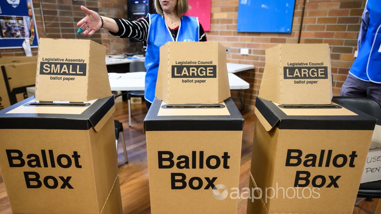 An election officer points to ballot boxes on NSW state election day