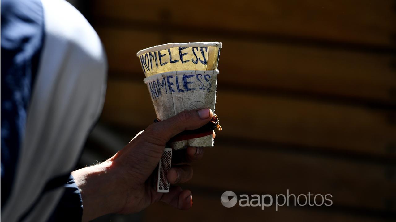 A homeless man holds a cup as he begs in Melbourne (file image)