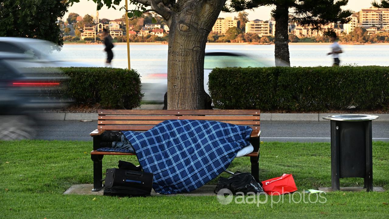A homeless person sleeping on a park bench in Perth (file image)