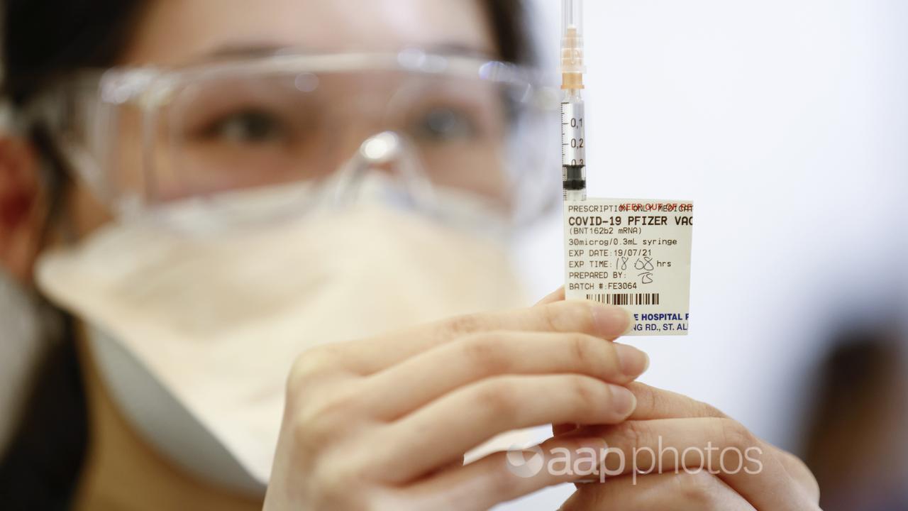 A health worker inspects a Pfizer syringe (file image)