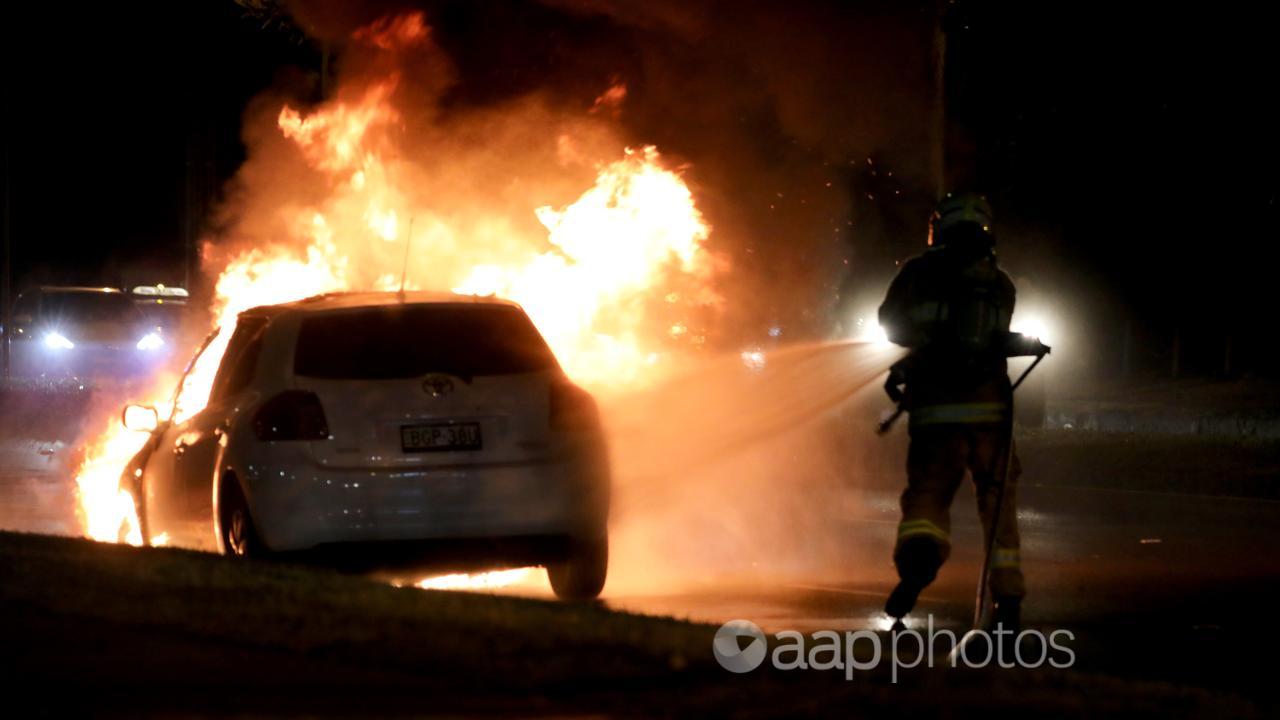 A firefighter attends to a car in flames (file image)