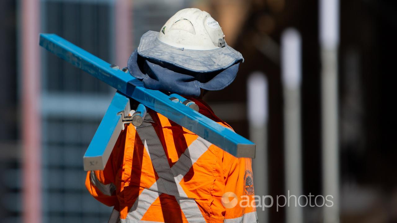 A constriction worker carries steal beams