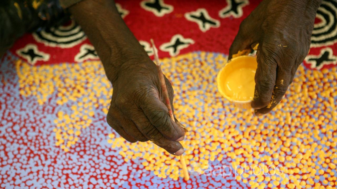 Aboriginal artist Paddy Stewart works on a dot painting (file image)