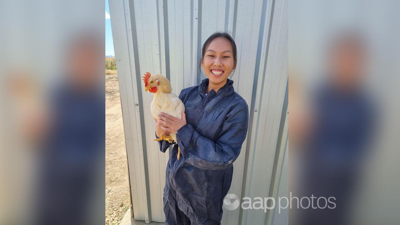 Tirza Winarta poses for a photo with a chicken.