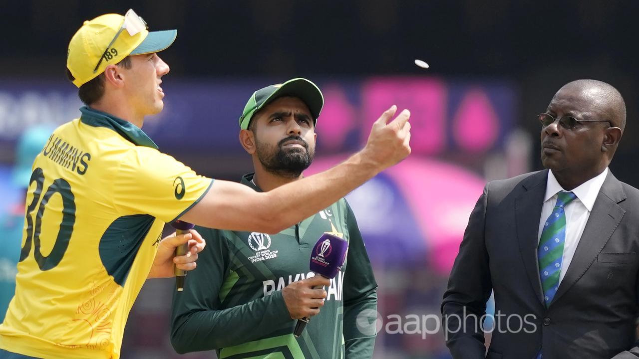 Pat Cummins tosses the coin watched by Pakistan's Babar Azam.