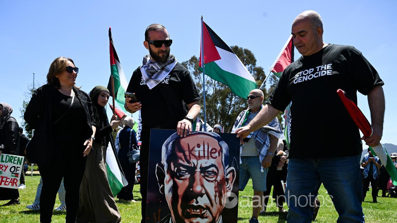 Protesters hold a corflute depicting Israel's PM Benjamin Netanyahu