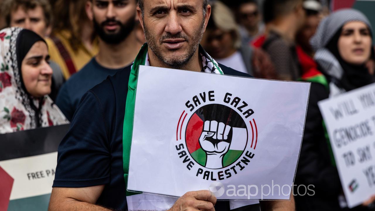 A pro-Palestine supporter holds a banner in Melbourne.