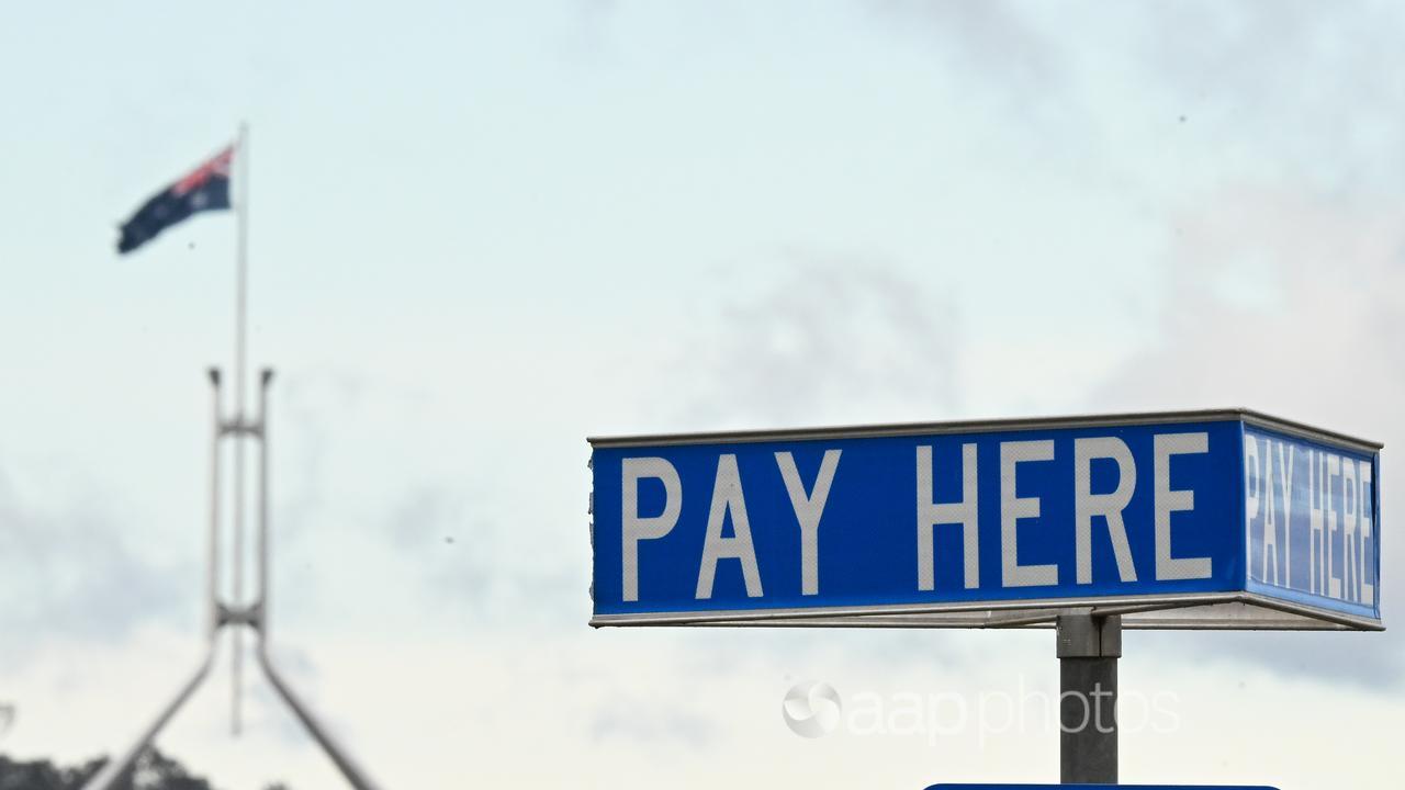 Australian Parliament House is seen behind a ‘Pay Here’ sign.