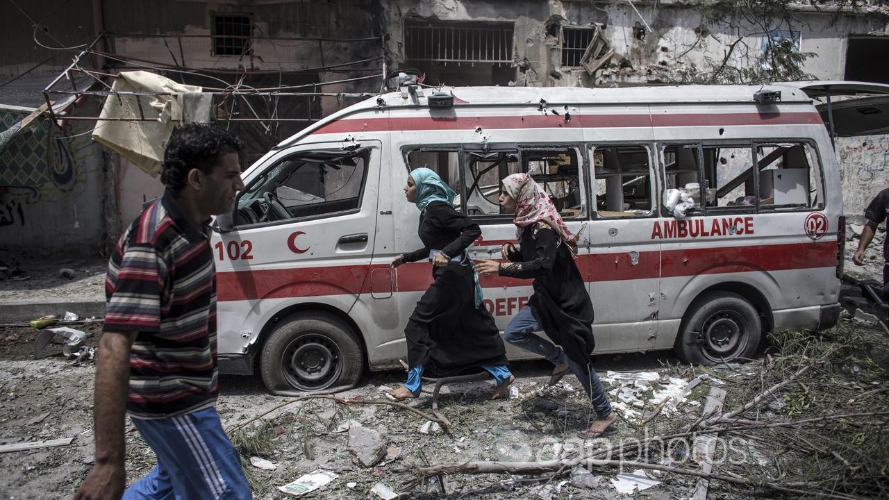 Palestinian girls run past a destroyed ambulance (file image)