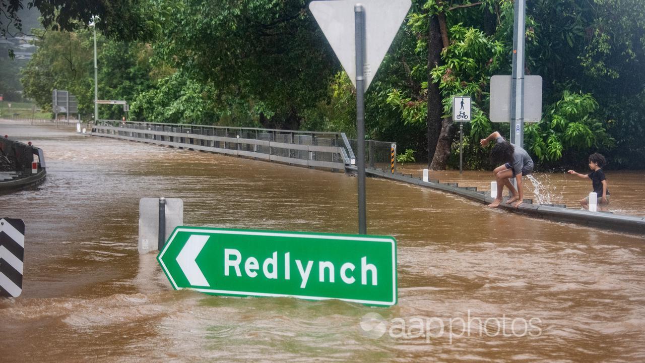 Children walk through flood waters near Redlynch in Cairns.