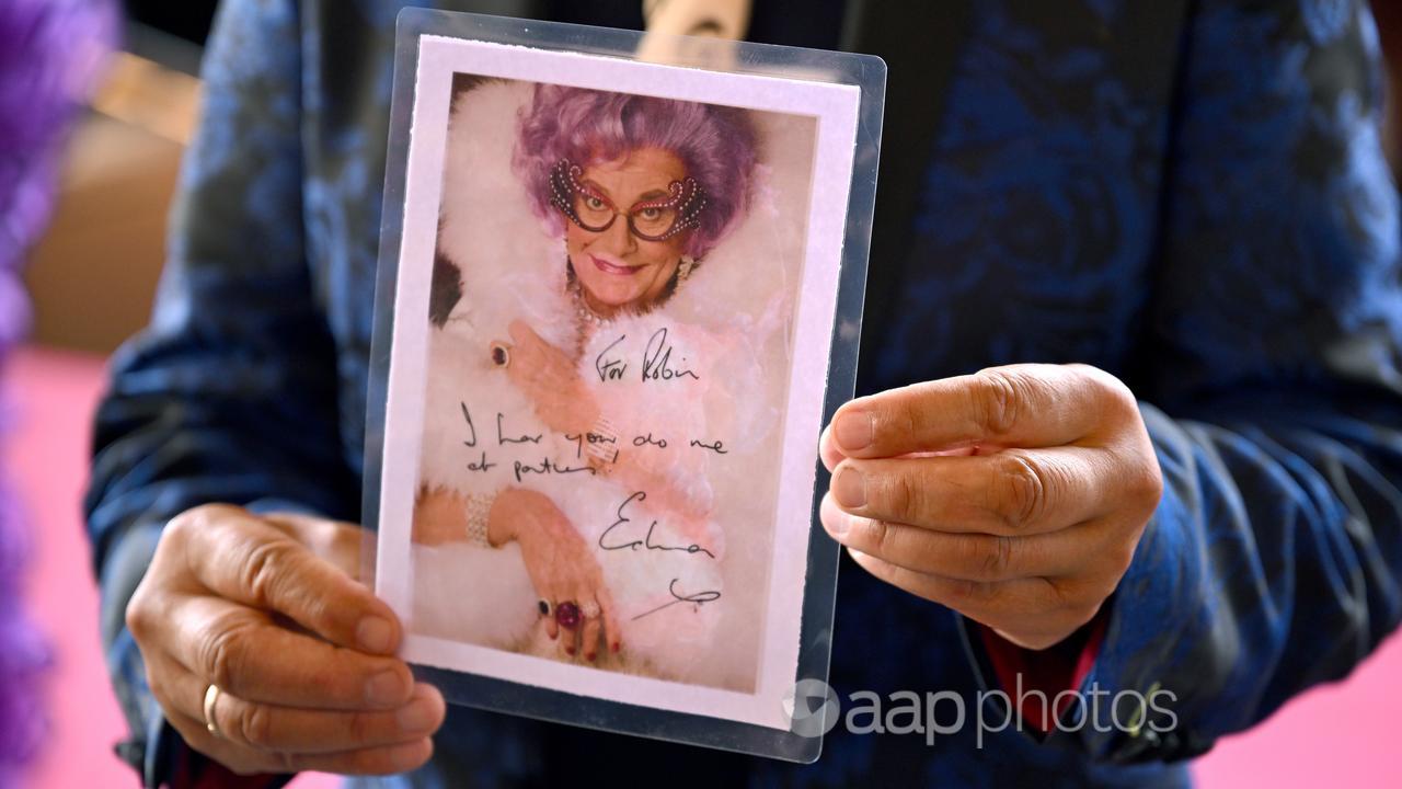 Memorial attendee holds a personalised message from Dame Edna.