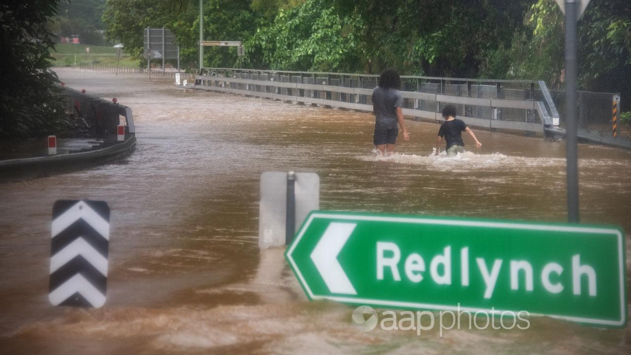 Children walk through flood waters near Redlynch in Cairns