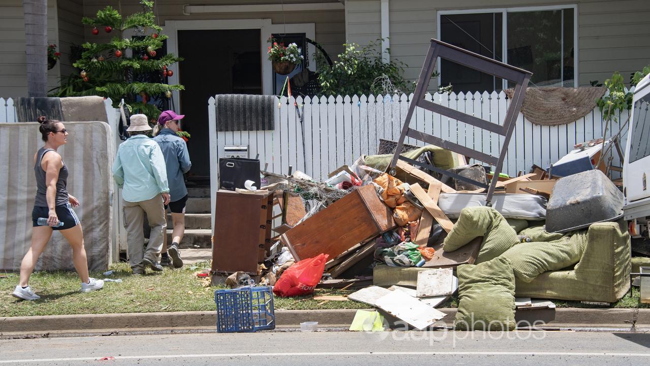Volunteers and furniture outside a home damaged by flooding in Cairns.