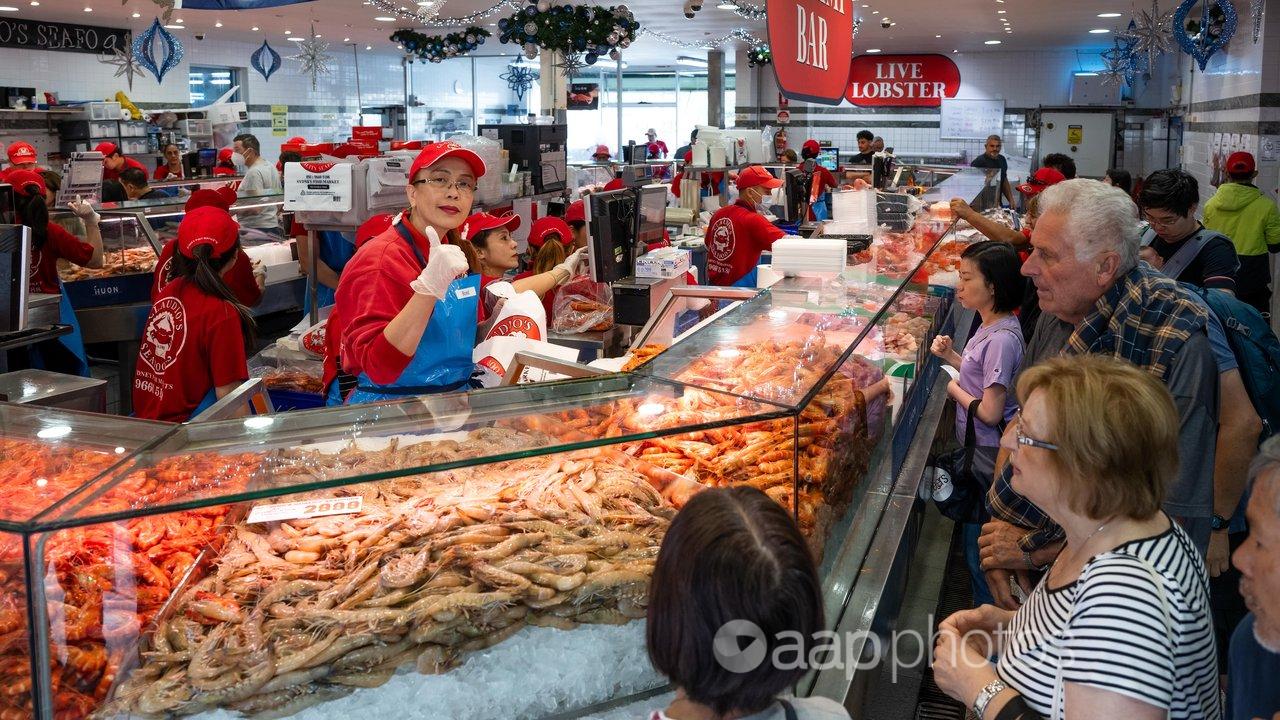 A seafood trader gives the thumbs up over a pile of prawns.