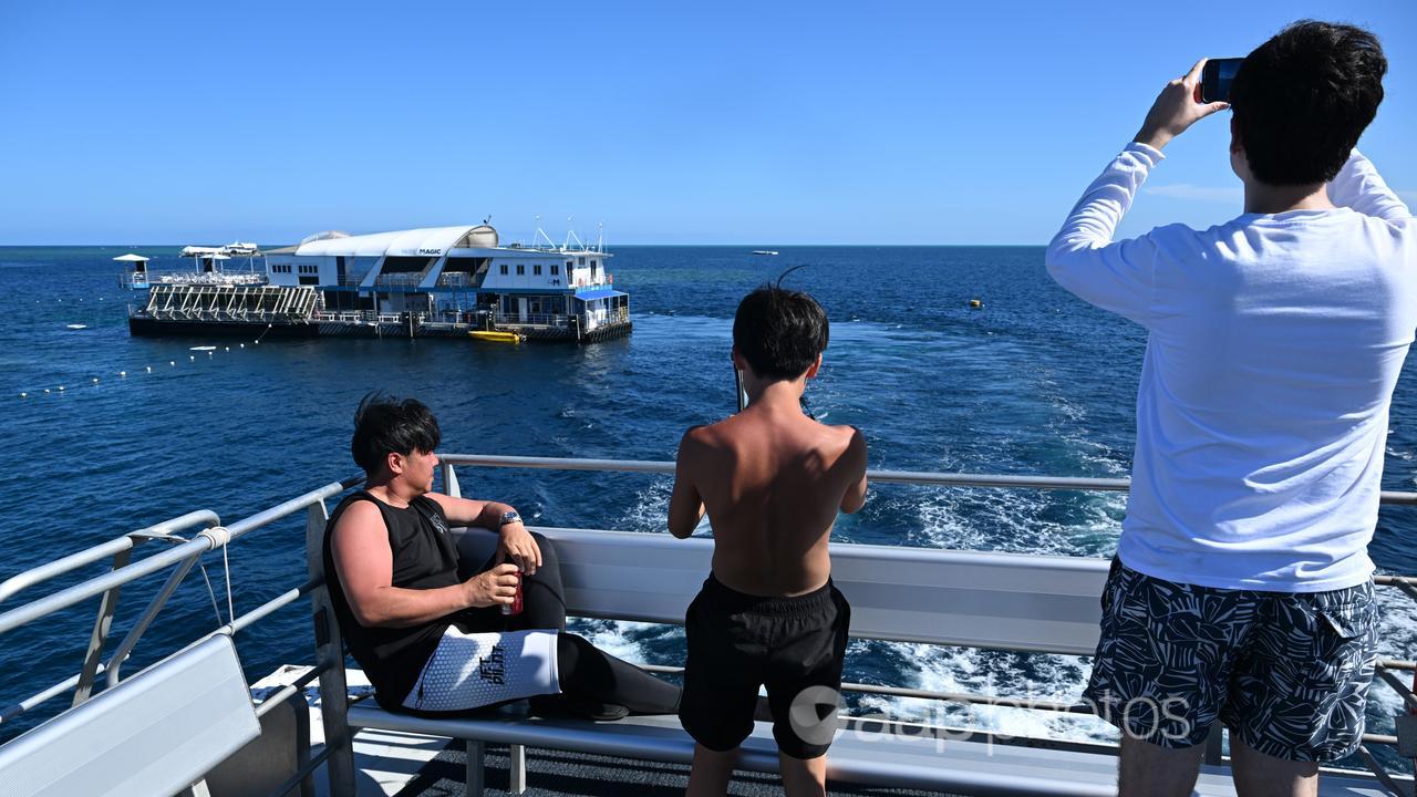 Tourists taking photographs of the Reef Magic pontoon at Moore Reef