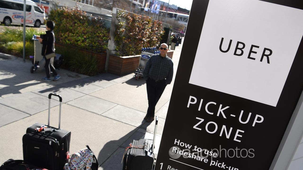 Travellers wait at the new designated pick-up zone for Uber
