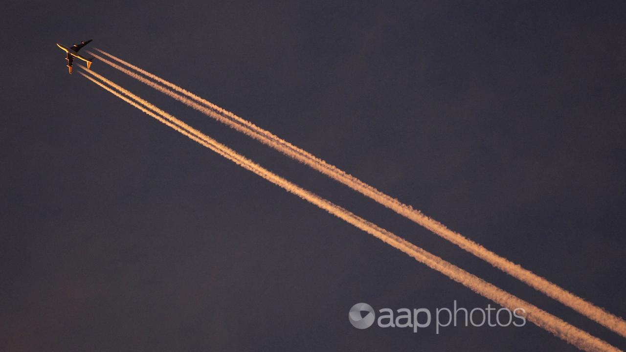 A plane in the evening sky with condensation trails