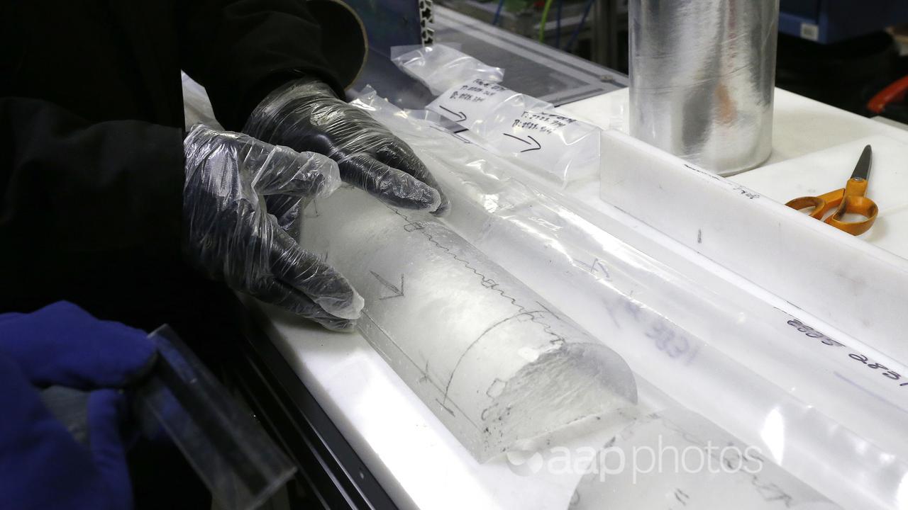 Man places an ice core inside the deep freeze work area at the lab