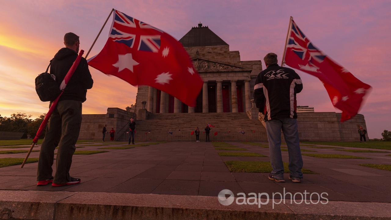 Two men holding the Red Ensign flag at the Dawn Service in Melbourne.