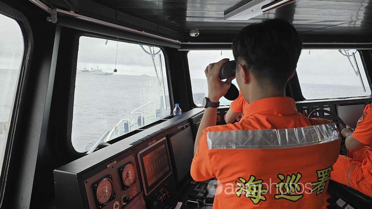 A Taiwan Coast Guard member monitors a Chinee ship.