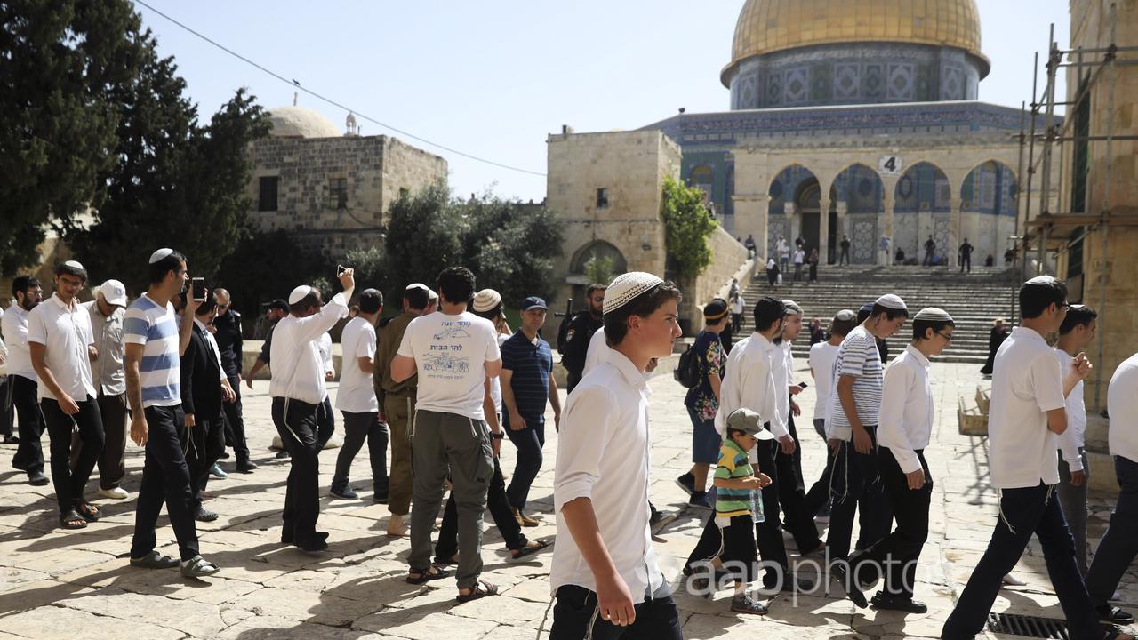 Israelis walk by the Dome of the Rock Mosque
