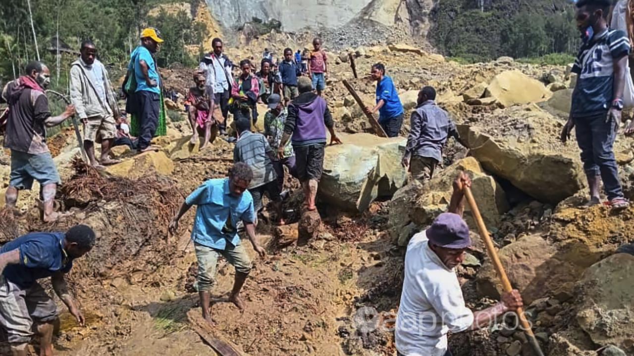 Villagers search through a landslide in Yambali