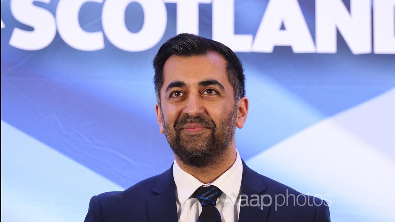 Humza Yousaf stands in front of a backdrop with the word 'Scotland'.